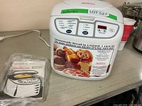 Sunbeam ExpressBake bread maker with instruction manual on a counter. Bread maker is white with controls visible.