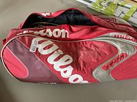 Wilson red and maroon tennis bag with white branding, zippered and partially open
