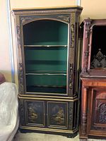 Full front view of the black and gold Chinoiserie cabinet showing glass shelves and decorated lower doors.