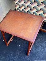 Top and side angle showing rectangular surface with minor scratches and knicks in the medium brown wooden finish on mid-century modern style side table.