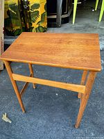 View of the mid-century modern side table showing the rectangular top and tapered legs in a varnished natural wood finish.