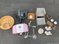 Photo showing entire mixed lot on concrete surface: includes Sunbeam grill, Black & Decker jigsaw, wooden tray, stoneware planter, various ceramic items and utensils