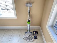 Full view of Bissell PowerFresh steam cleaner standing upright with microfiber mop pads and two small boxes on floor next to it.
