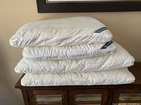 Four white pillows stacked: two Serta Pedic standard pillows on top of two Beauty Rest king pillows.