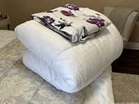 Full view of white King SertaPedic comforter folded with floral cover on top.
