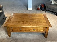 Front view of solid oak coffee table showing the storage drawer and top surface with wood grain.
