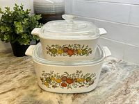 Casseroles stacked with lids on, showing front vegetable pattern.