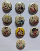Photo showing all 10 vintage Kellogg's Pep buttons with cartoon character illustrations laid out on a white background, showing signs of aging and wear.