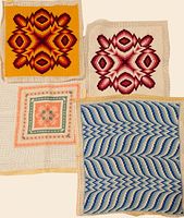 Four needlepoint canvases laid flat showing various colorful geometric and floral stitched patterns on woven mesh fabric.
