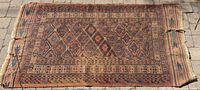 Full view of the antique handmade rug showing geometric patterns and overall wear.