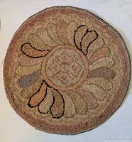 Full top view of the circular hooked textile seat cover showing overall pattern and muted earthy colors.