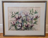 Framed watercolour painting showing the full artwork of magnolia flowers with purple and pink petals and green leaves.