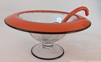 Footed glass bowl with orange rim and black edging, displaying the bowl's depth and size.