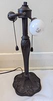 Full view of the lamp base showing two bulb sockets with pull chains, one bulb socket with a globe bulb, and the overall Art Nouveau styling.