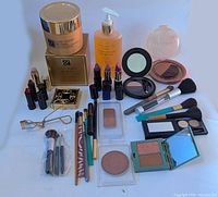 Full lot of makeup products including creams, lipsticks, brushes, powders, eyelash curler, and lotion bottle