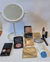 Overview of the lot including standing makeup mirror and various makeup items on a wooden surface.