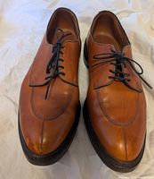 Front view of both shoes showing walnut leather upper with split toe design and black laces. Visible scuff at the toe tip of left shoe.