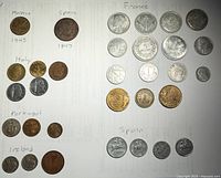 Full collection of 27 coins from multiple countries arranged on paper labeled by country and year.
