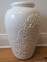 Front view of large white ceramic vase showing its shape and rose embossed motif.