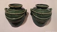 Two green glazed ceramic planters side by side showing overall shape and glaze.