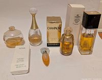 Seven assorted perfume bottles and boxes on white surface