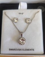 Full set of Swarovski Elements crystal pendant necklace and matching stud earrings displayed on white cushion with label showing chain length 16+3 inches.