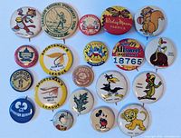 Top view of the full set of 18 vintage promotional buttons, colorful cartoon characters and various advertising logos visible.