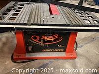 Side view of table saw showing Black and Decker branding, 15 amp motor specification and orange adjustment handles.