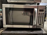 Front view of a Danby stainless steel microwave oven showing the door, handle, and digital control panel keypad on the right.