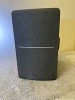 Front view of the Edifier speaker with black fabric front and silver line in center, showing Edifier logo at bottom.