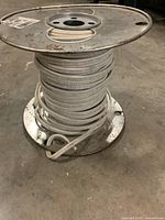 Metal spool wound with white 14-2 NMD90 electrical wire, showing overall size and coil.