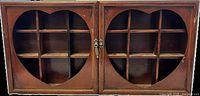 Front view of wooden cabinet with two heart-shaped windows on doors showing internal compartments