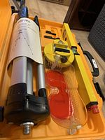 Johnson laser level mounted on tripod with yellow level and safety goggles inside the case.