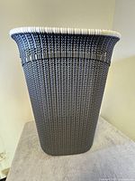 Front view showing the tall rectangular shape and dark woven plastic texture with a light rim.