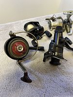Four used fishing reels on a light cloth surface showing condition and variety.