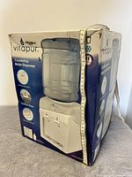 Front and side views of the boxed Vitapur countertop water dispenser, showing product details and condition of packaging.