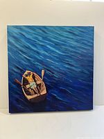 Full view of the square acrylic painting showing a man relaxing in a wooden rowboat floating on blue water.