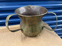 Front and side view of antique brass pot showing wide body, three handles, and patina.