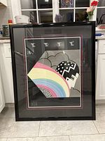 Framed Erte poster displayed vertically on tiled floor, showing full artwork and black frame.
