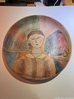 Front view showing hand painted portrait of a woman on circular charger.