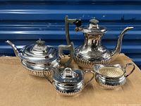 Full view of 4-piece silver plate tea and coffee service including coffee pot with handle and spout, teapot, sugar bowl with lid, and creamer pitcher.