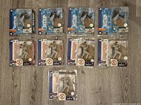 Top view photo of nine McFarlane MLB baseball figures in original packaging placed on floor, showing player poses and packaging condition.