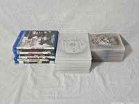 Blu-ray movie lot showing stack of original cases with cover art and two stacks of discs only in clear plastic sleeves.