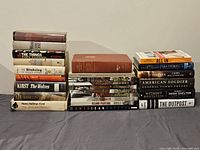 Photo showing a stacked assortment of 19 books with titles relating to military and World War II history. Books show various spine conditions.