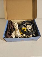 Photo showing an open box filled with assorted cables and cords in various colors and types.