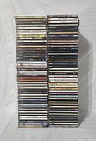 Front view of three stacks of used CD jewel cases showing a mix of artists and soundtracks in used condition.