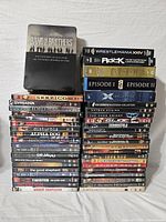 Photo showing full lot stacked with clear visibility of DVD titles including Band of Brothers tin set, assorted movies and wrestling DVDs.