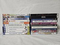Photo showing stacked DVD cases labeled with various workout titles including Pilates, Jillian Michaels, Cardio Dance, and others.
