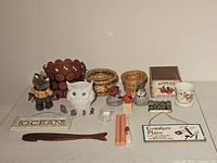 Overview photo showing the various home decor items arranged on a white surface including woven baskets, decorative owls, bird figurines, signs, candles, and trays.