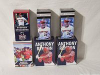Photo showing boxed Stephen Strasburg and Aaron Barrett bobbleheads on the left with Anthony Rendon boxes in the center and right side and Matt Lecroy boxes behind them.